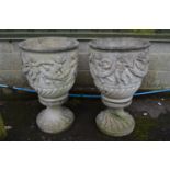 Pair of circular garden urns decorated with figures of dancing cherubs and swags, standing on