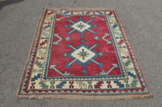 Red ground rug with blue, white and green pattern with end tassels - 1.92cm x 1.22cm Please note