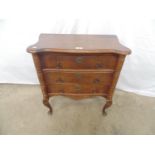 Small oak chest of drawers having a shaped top over three drawers, standing on cabriole legs -