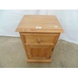 Modern pine bedside cupboard having a single drawer over cupboard base, standing on a plinth