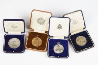 A collection of four cased coins and sporting medals.