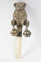 An antique sterling silver babies rattle in the form of a bear.