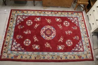 Large Chinese style Red Ground Rug decorated with flowers within a pale green border decorated