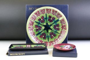 Three boxed Moorcroft pottery dishes to include a Violet pattern green ground circular dish (date