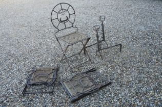 Three cast iron folding chairs with stylised face to back and woven seats, together with a pair of