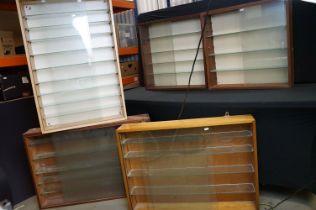 Collection of eight wall mounted wooden display cabinets with sliding glass fronts & glass