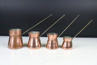 Set of Four Copper Pouring Measure Jugs with brass handles, the largest 17cm (to top of handle)