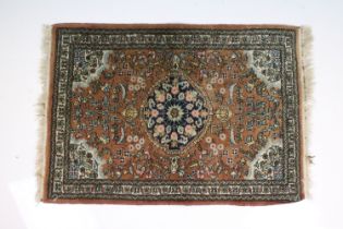 Small Red Ground Rug decorated with a stylised floral pattern, 90cm x 64cm