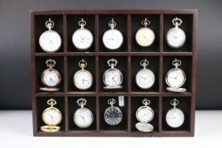 A collection of fifteen contemporary pocket watches contained within a wooden wall mounted display
