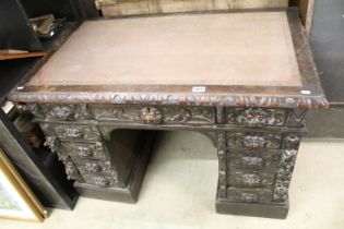 Victorian Carved Dark Oak Desk with brown leather inset top over an arrangement of nine heavily