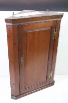 George III Oak Hanging Corner Cabinet, the single door opening to three shaped shelves, with key,