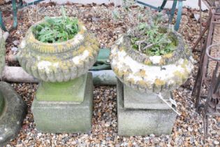 Pair of reconstituted stone garden planters of gadrooned form, raised on square stone plinths (