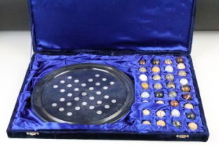 A cased carved stone solitaire set, polished agate balls with granite base in fitted velvet case.