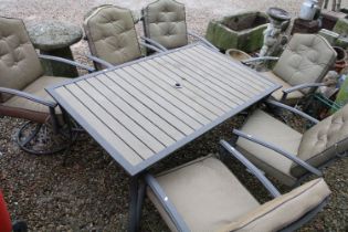 Metal garden patio table with six chairs (featuring two sprung chairs), complete with cushions. (