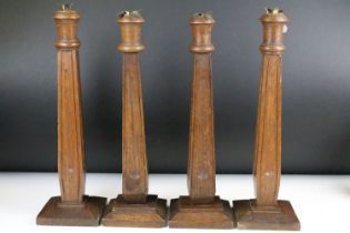 Two pairs of Arts & Crafts carved oak candlesticks of tapering form, raised on stepped square wooden