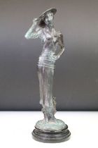 Bronze figure of a lady wearing a wide-brim hat, raised on a circular pedestal base. Measures approx