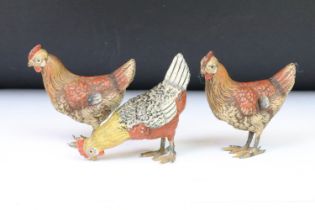 A collection of three ornamental cold painted metal chicken figures.