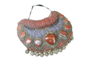 A large Tibetan neck piece adorned with nine large carnelian stones and a row of bells.