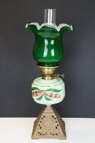 Late Victorian / early 20th Century oil lamp having a cast metal base, green glass reservoir with