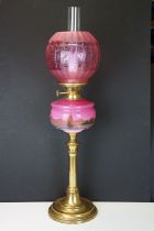 Late Victorian / early 20th Century oil lamp having a round brass stepped base, pink reservoir