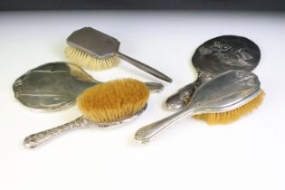 Five silver backed dressing table pieces to include two mirrors, and three hair brushes all with