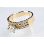 14ct gold and diamond ring. The ring being prong set with a round brilliant cut diamond with three