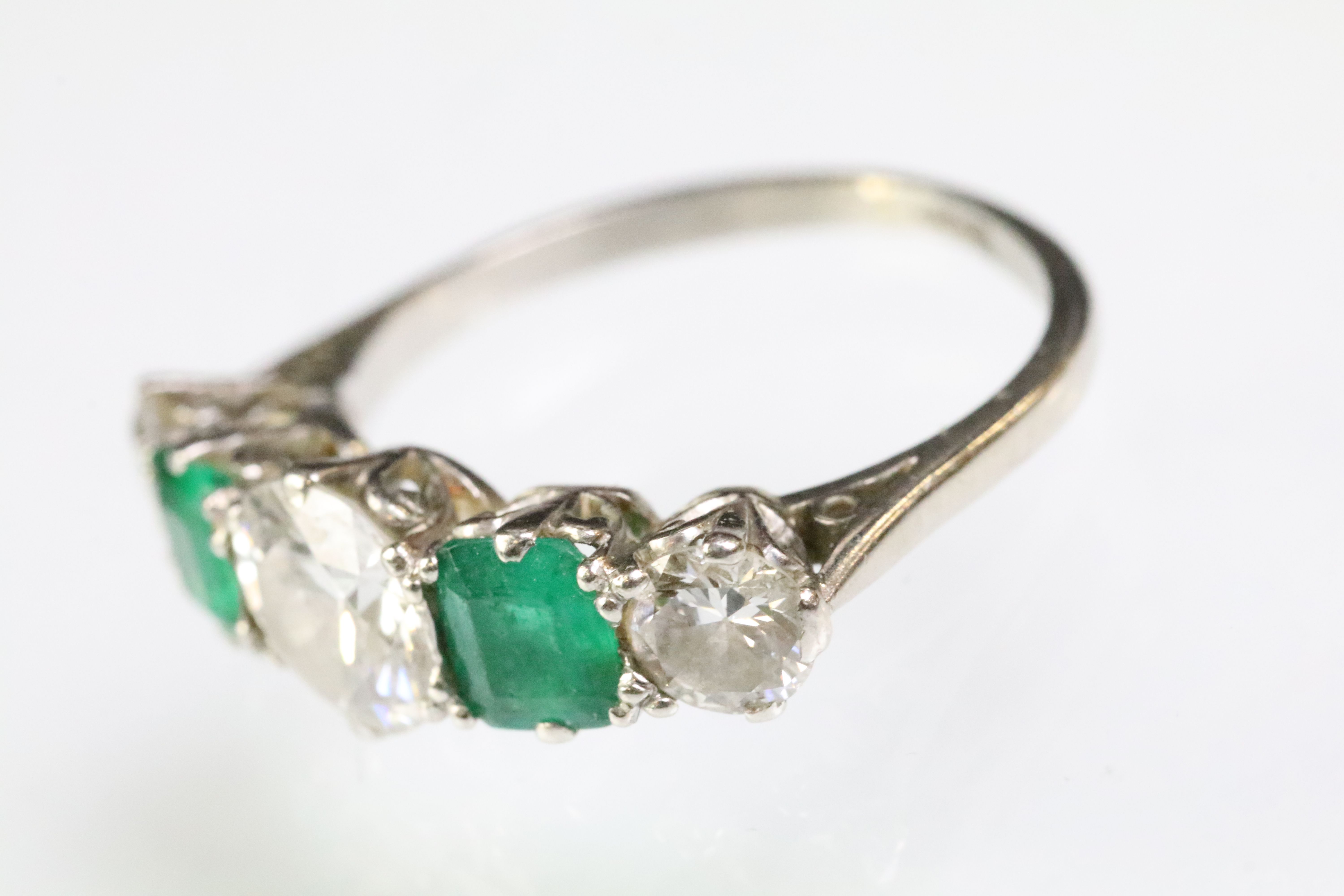 Diamond and emerald five stone ring being set with a round cut diamond to the centre flanked by
