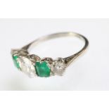 Diamond and emerald five stone ring being set with a round cut diamond to the centre flanked by