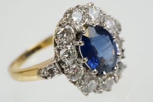 18ct gold, sapphire and diamond cluster ring being set with an oval mixed but clue sapphire with a