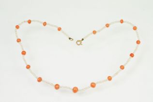 Coral and seed pearl beaded necklace being strung with round coral beads with small seed pearls