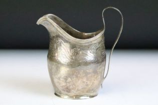 19th Century George III silver cream jug having engraved foliate scrolls and banded rim.