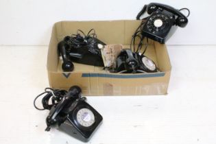 Four free standing black plastic ring dial telephones with emergency directory panels to the centre.