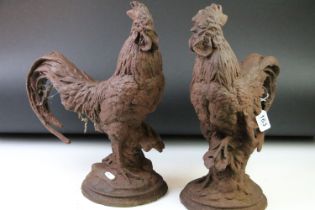 Pair of cast iron garden cockerel ornaments, raised on circular bases, with oxidised finish. (