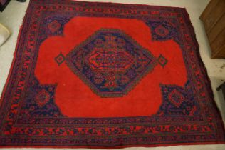 Large Wool Red Ground Rug with central geometric pattern motif and border to edge, 320cm x 373cm