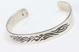 A contemporary 925 sterling silver open ended cuff bangle with engraved tribal decoration, marked