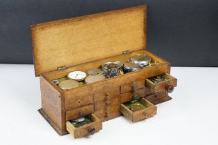 A wooden watchmakers box together with contents to include wristwatches, pocket watches and parts.