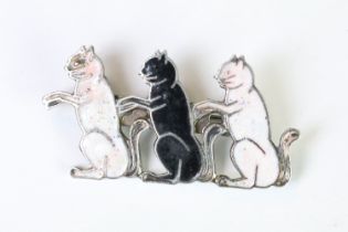 A silver plated and enamel brooch in the form of three seated cats.