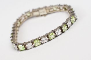A contemporary 925 sterling silver tennis bracelet set with light green and clear stones, complete