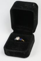 A silver gilt ladies dress ring with clear centre stone and blue stones set to either side.