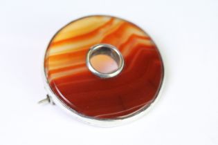 A Victorian Scottish silver and carnelian brooch of circular form, unmarked white metal tests as
