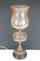 Late 19th / early 20th century oil lamp, the pink glass frosted shade with floral detail, over a