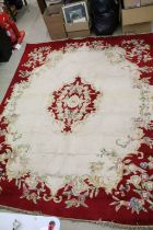 Large red ground wool floor rug with floral decoration, fringe to either end, measures approx