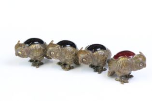 A set of four bronze owl figures set with coloured glass backs.