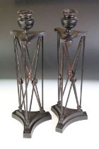 Pair of cast metal candlesticks of architectural form with acorn details, raised on triform bases,