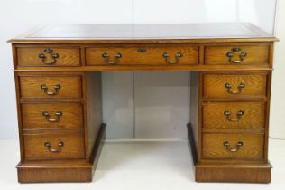 Oak twin pedestal desk, with red leather inset top and an arrangement of nine drawers, with key,