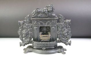Cast iron miniature fireplace with fire guard, surmounted by a lion, raised on four feet, measures