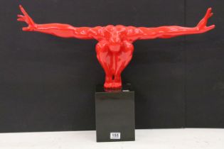 Cast resin shop display figure in the form of a red crouching man mounted to a black marble block