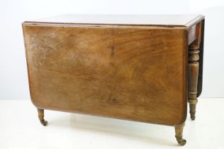 19th century mahogany drop leaf table, on turned tapering legs with brass casters, 73cm high x 161cm