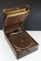 A vintage HMV portable wind up record player together with a quantity of records.