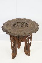 Indian carved hardwood occasional table, the top carved with a central panel depicting three